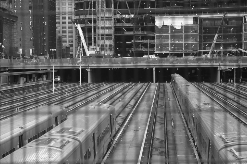 Trains lined up beneath a station, black and white