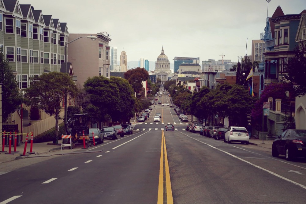 A wide city street running down towards a domed building